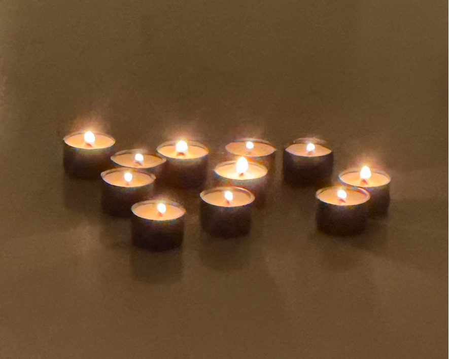 Tea lights arranged  on a reflective surface.